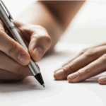 紙にペンで文字を書いている